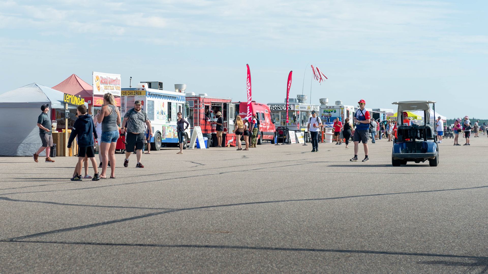 Food trucks and visitors at Cold Lake Air Show under a sunny sky.