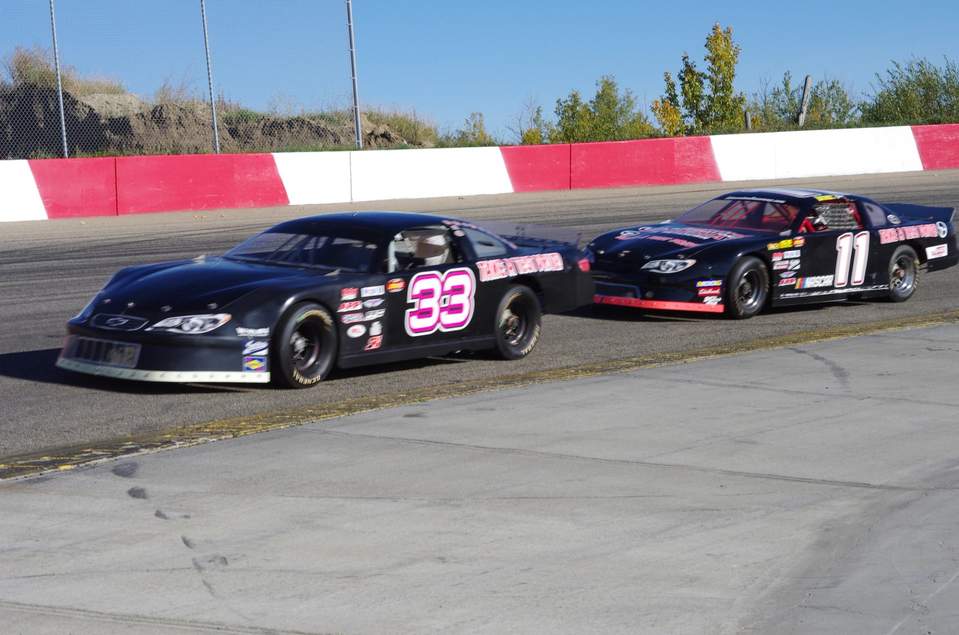 Two NASCAR stock cars on a racetrack, numbered 33 and 11.