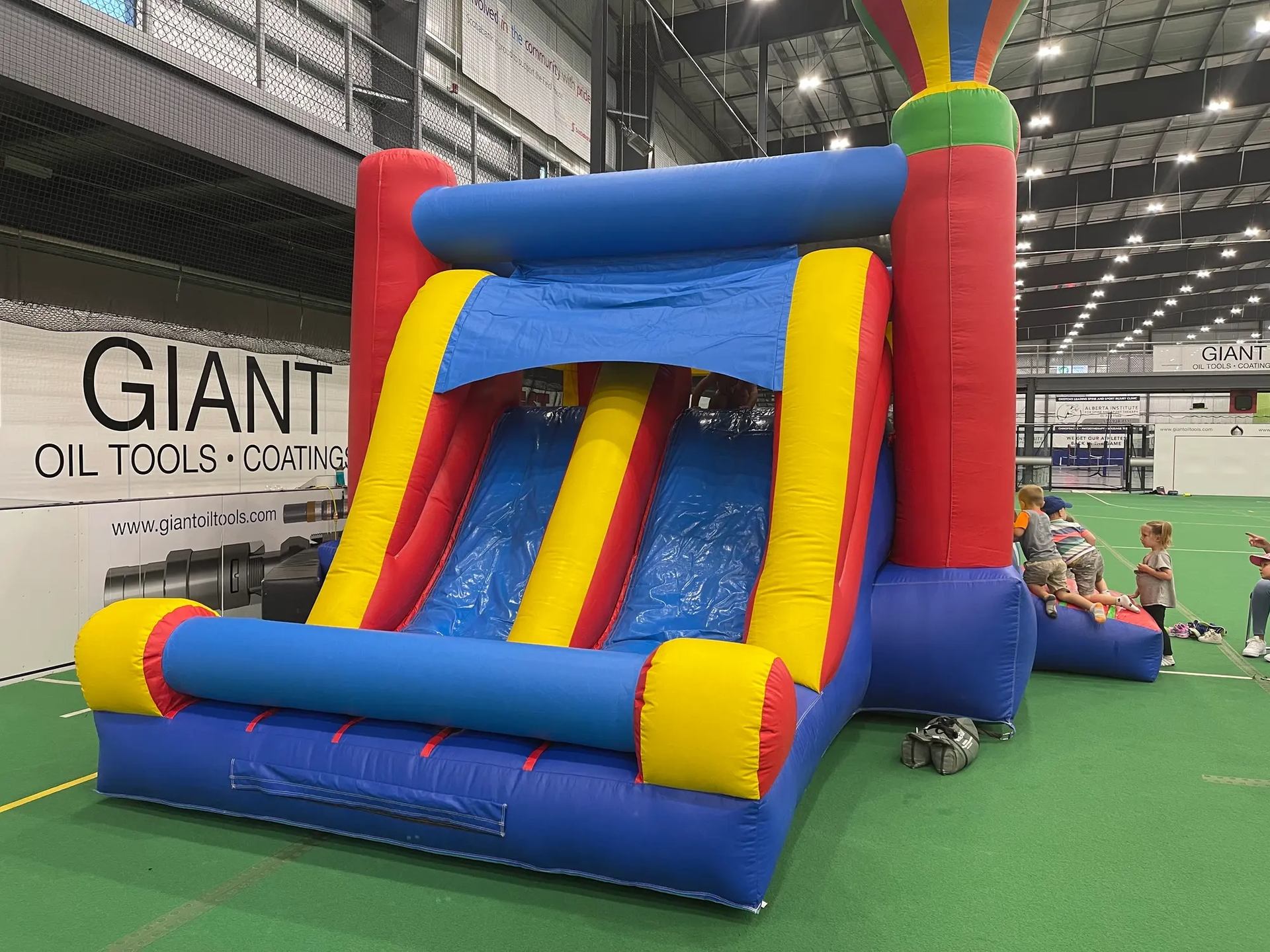 Kids playing on a large inflatable slide at Regional Field House indoor playground.