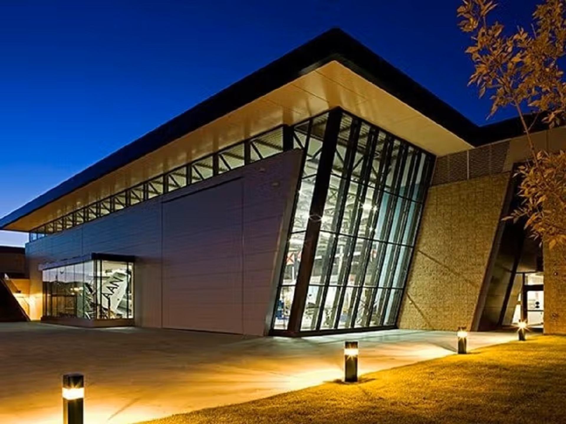 Modern museum building with glass windows lit up at dusk.