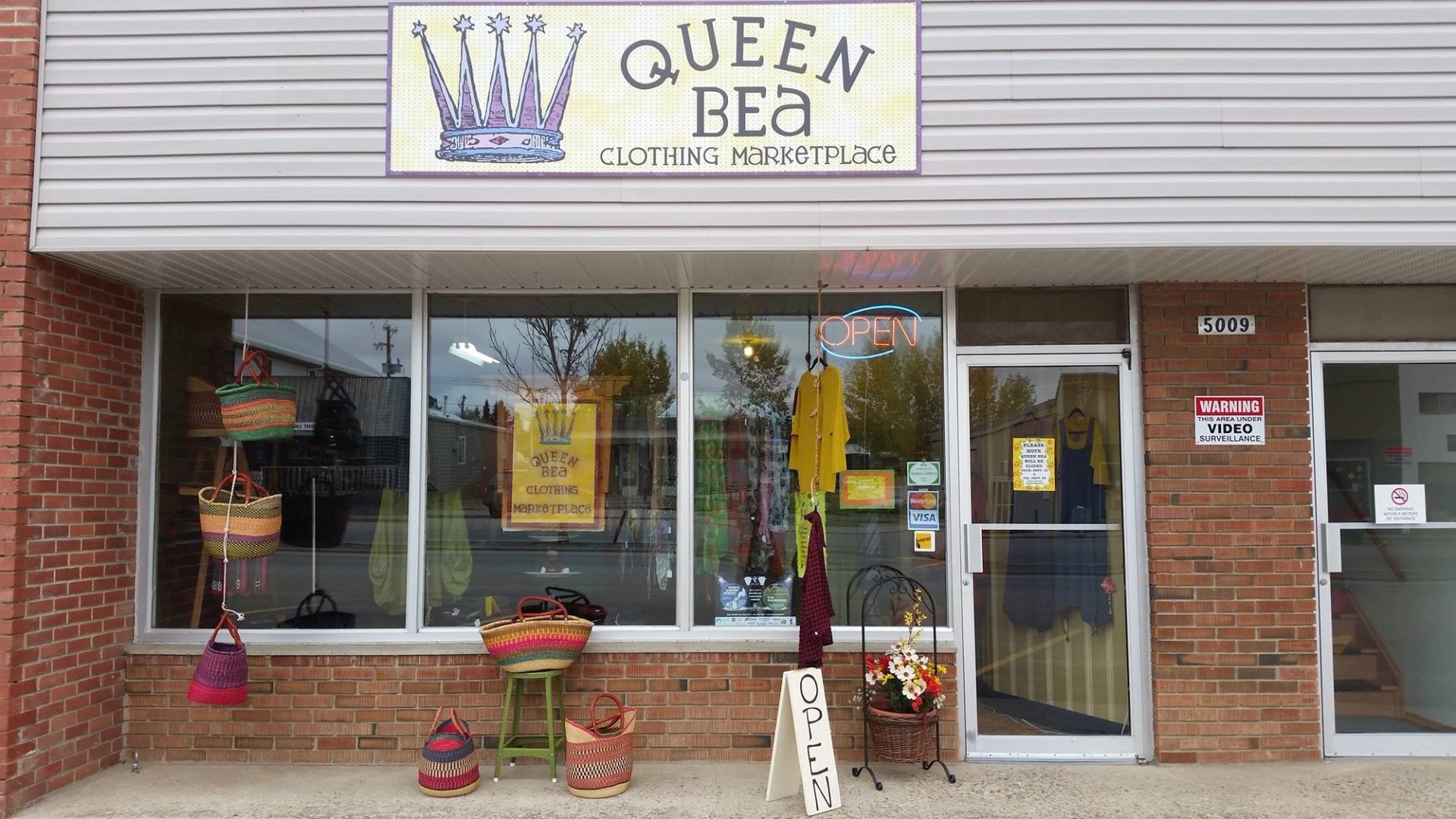 Exterior of Queen Bea Clothing Marketplace with baskets and an open sign.