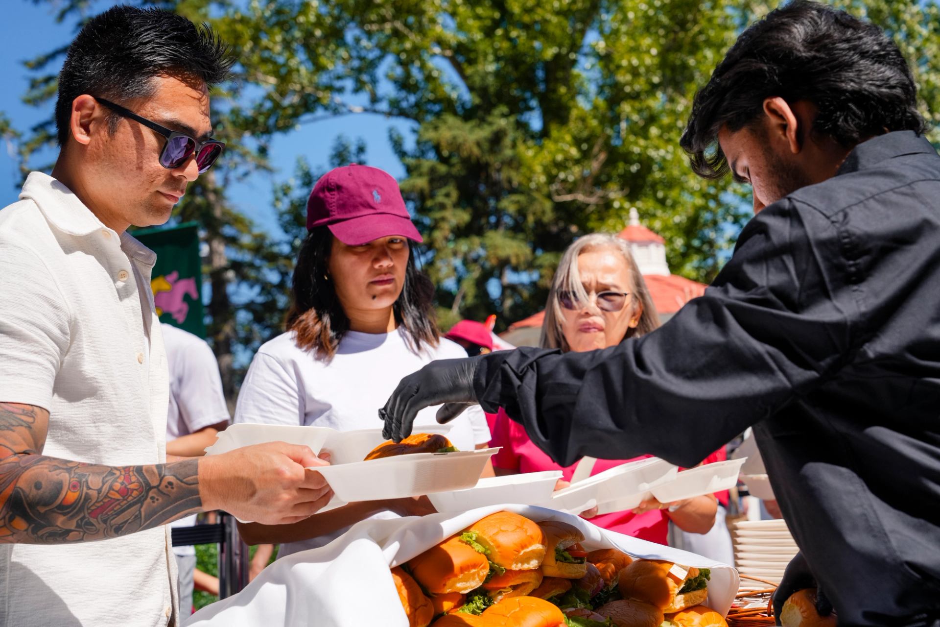 Food vendor handing out plates of burgers at an outdoor event booth