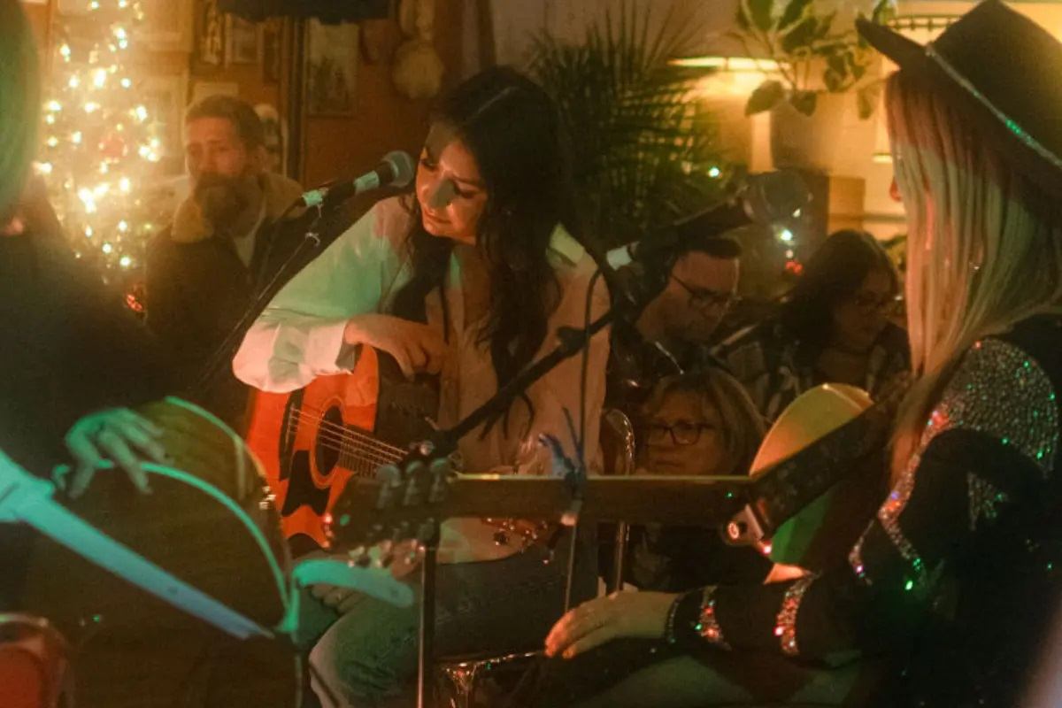 Musicians play acoustic instruments together in a warmly lit indoor space at Blue Jay Sessions: Winter Edition.