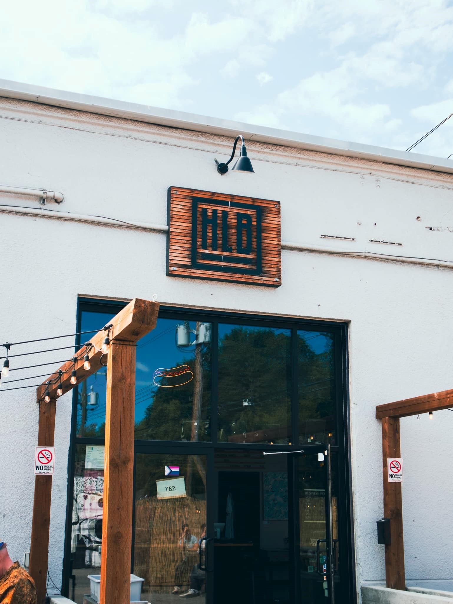 High Line Brewing sign on wooden panel above storefront window, with neon beer icon inside.
