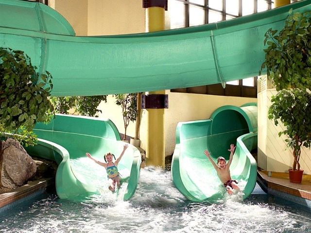 Kids splash down green water slides at indoor pool in Sheraton Cavalier Calgary.
