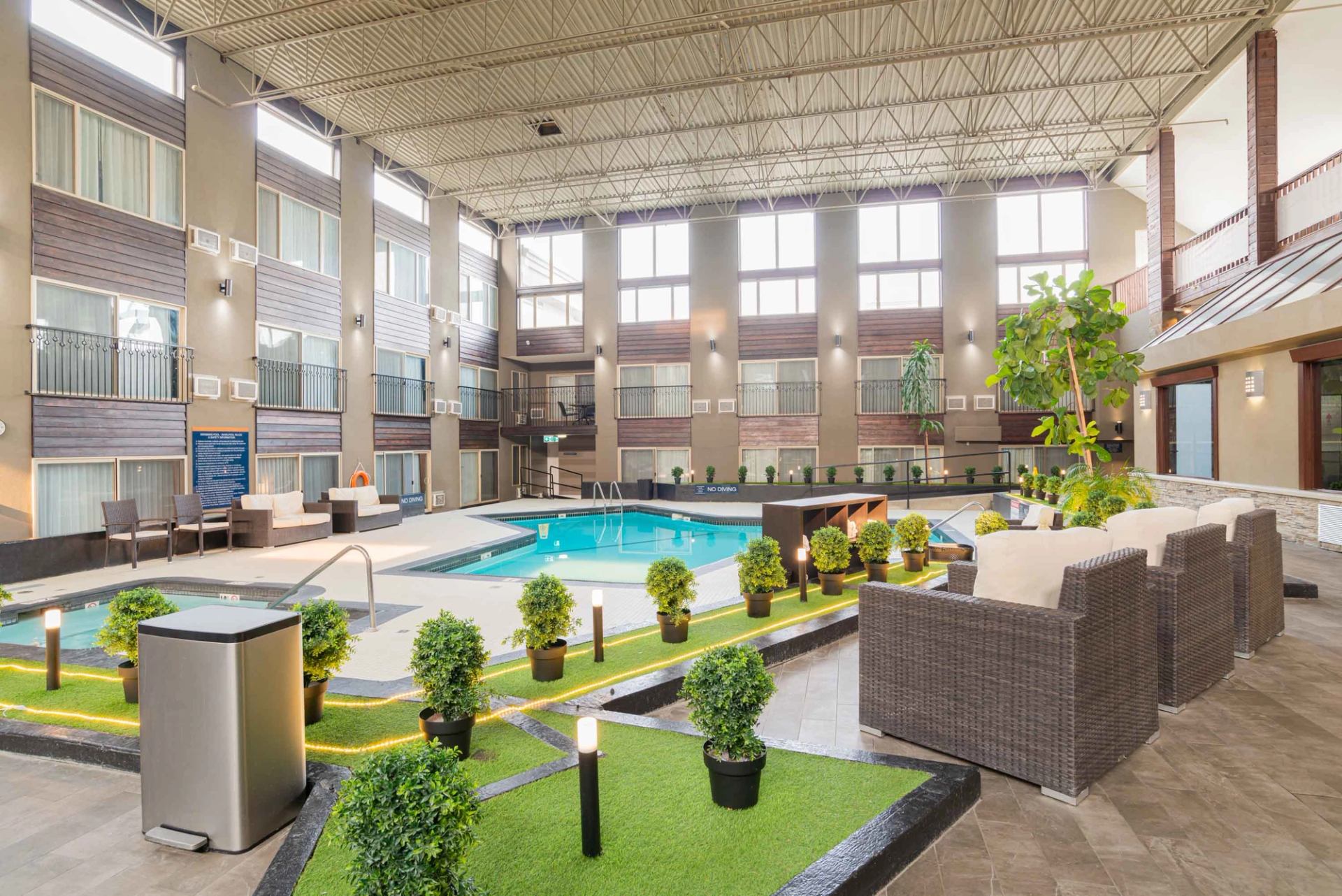 Large indoor pool atrium with seating areas, plants, and natural light.