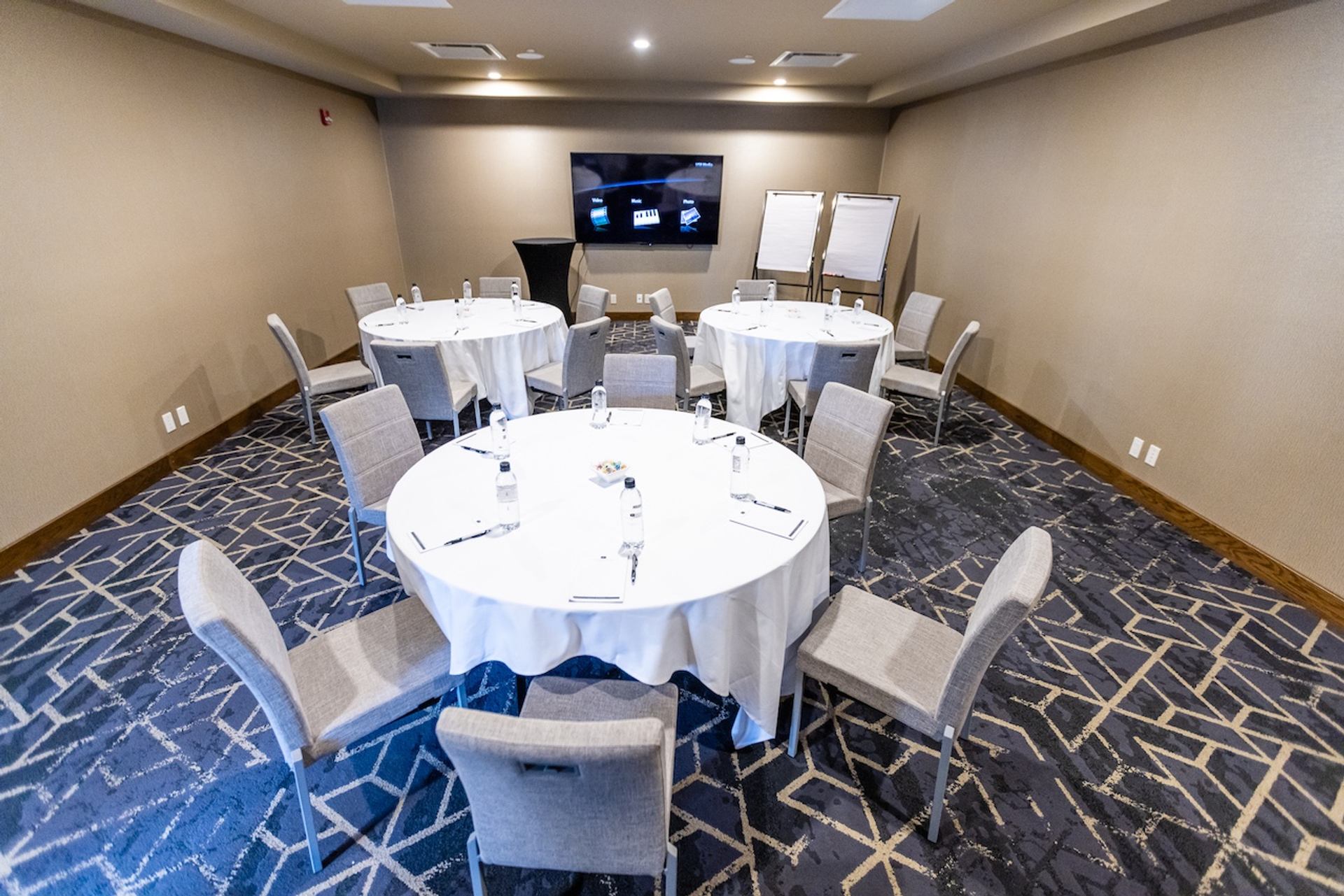 Meeting room with round tables, chairs, and a screen for presentations