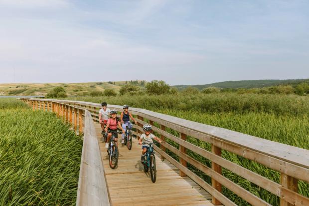 Family biking along a boardwalk in Cypress Hills Provincial Park.