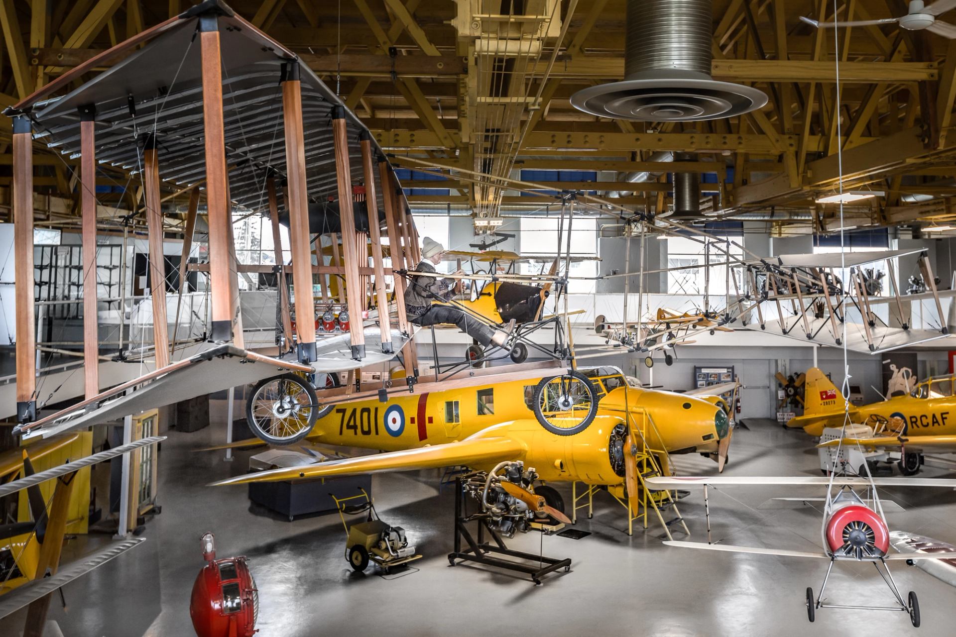 Historic aircraft displayed inside an aviation museum hangar, featuring fabric wings and wood framing.