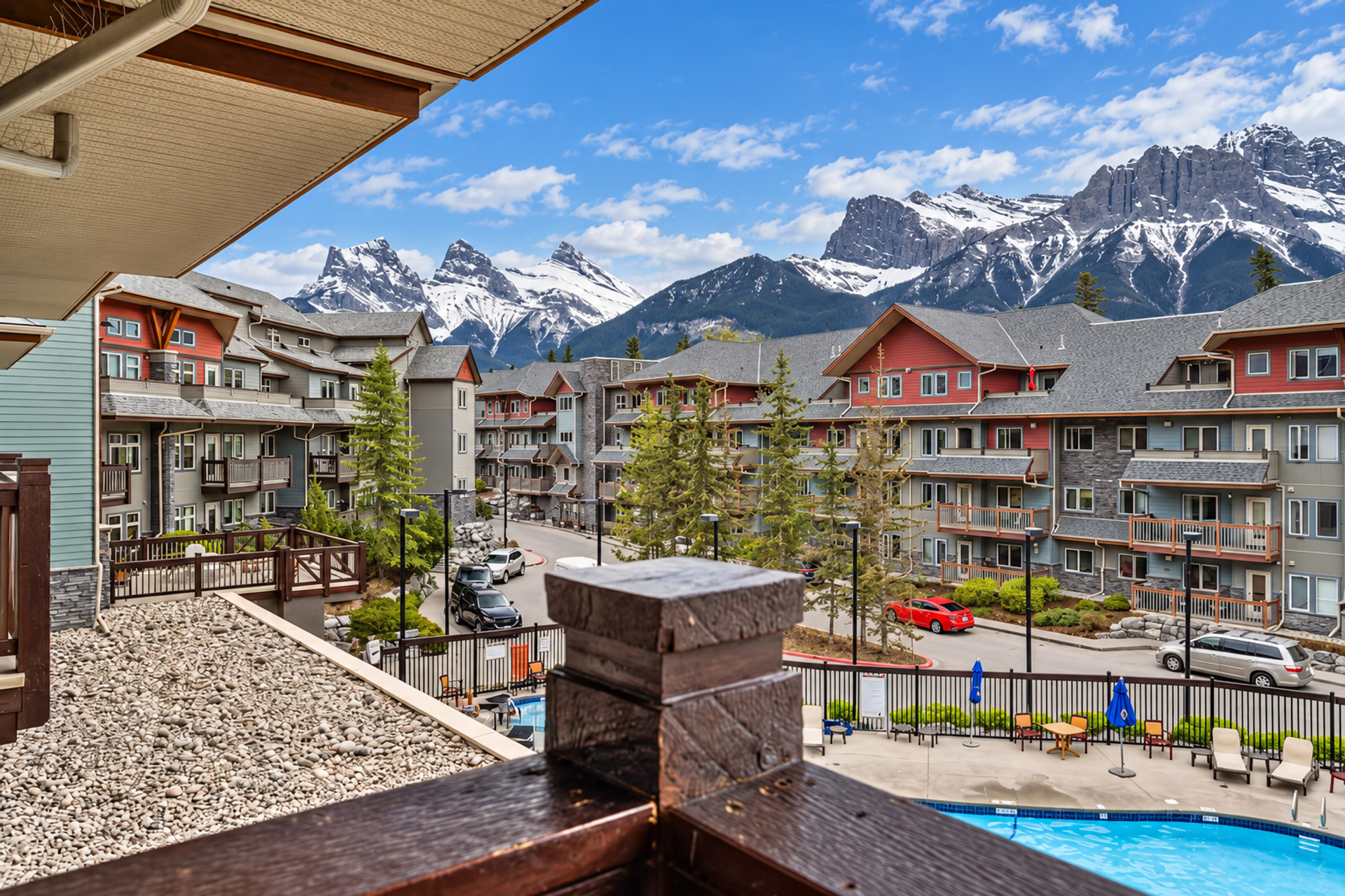 Mountain resort buildings and outdoor pool beneath snow-covered peaks.