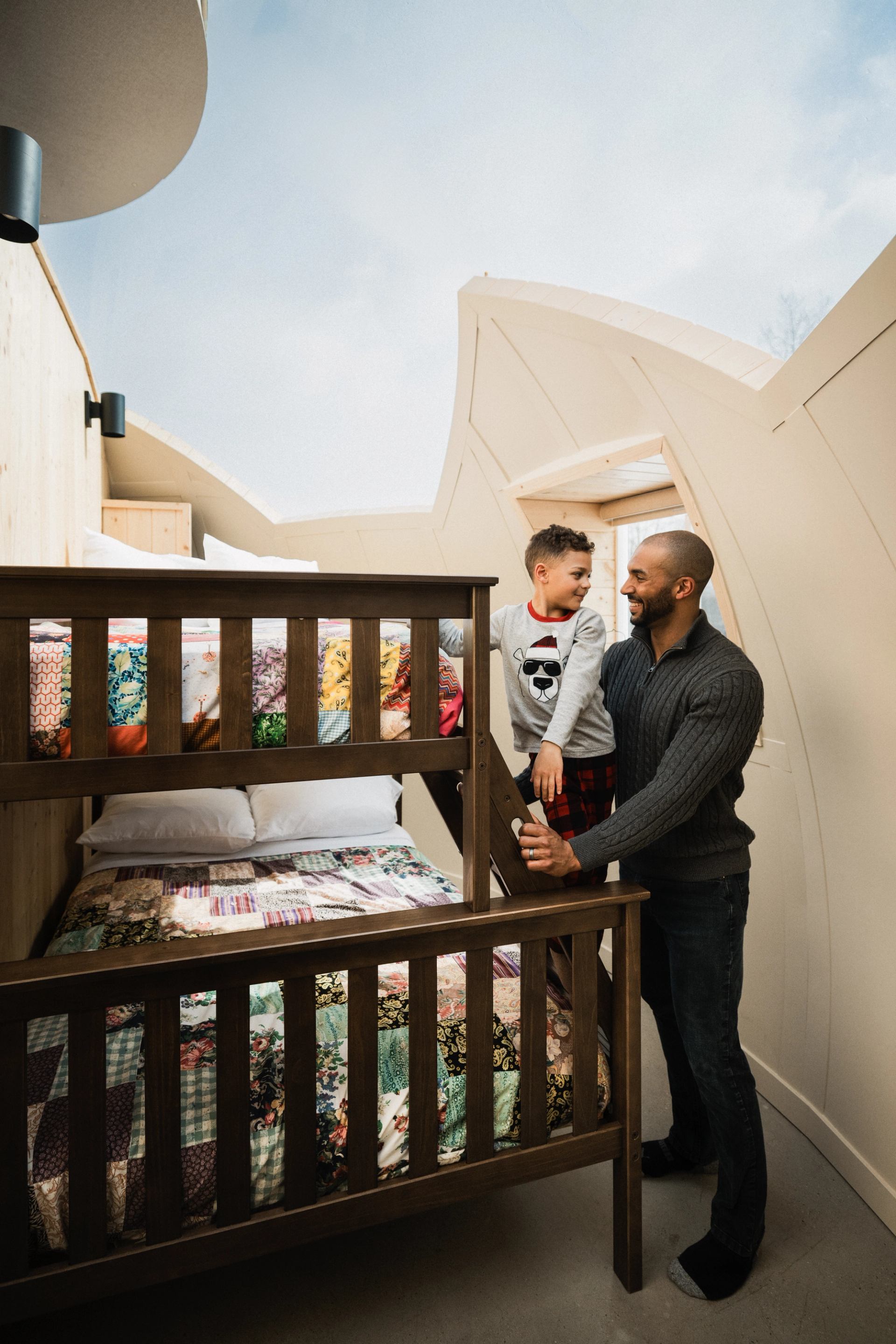 Two people by bunk bed in dome-shaped room at Métis Crossing Sky Watching Domes.