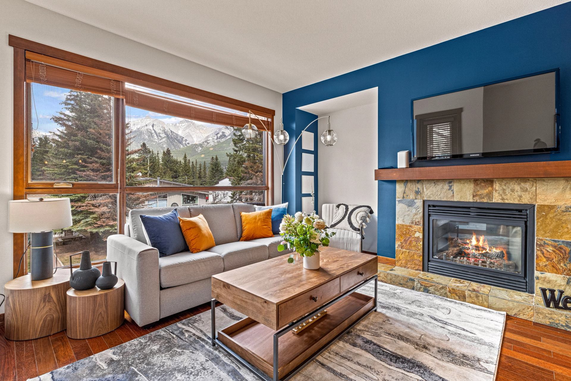 Living room with mountain view window, sofa, coffee table, and stone fireplace.