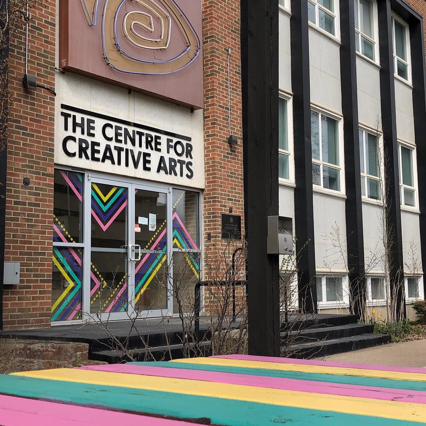 The Centre for Creative Arts entrance with sign, brick facade, and colorful window mural.