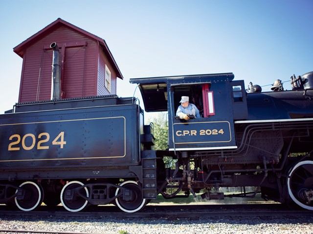 Vintage CPR 2024 steam train with engineer in cabin at Heritage Park.