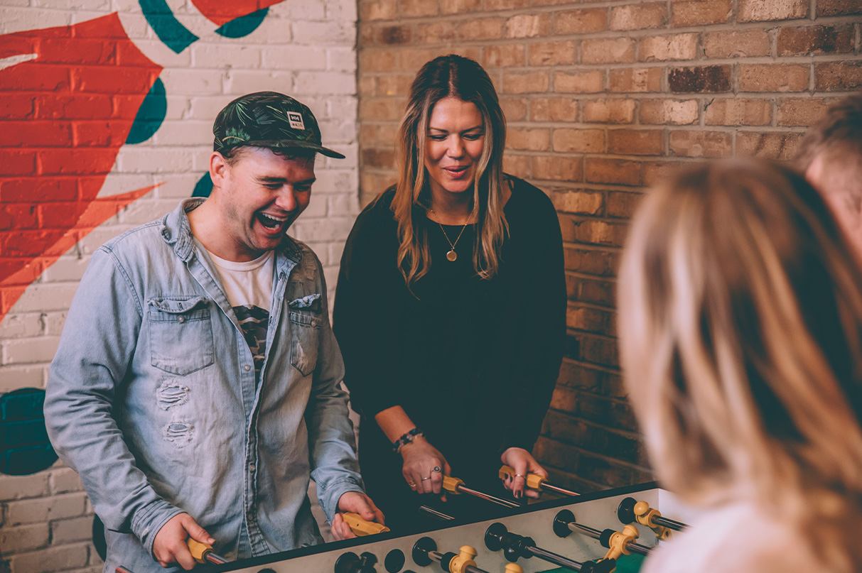 A group of 4 plays foosball.