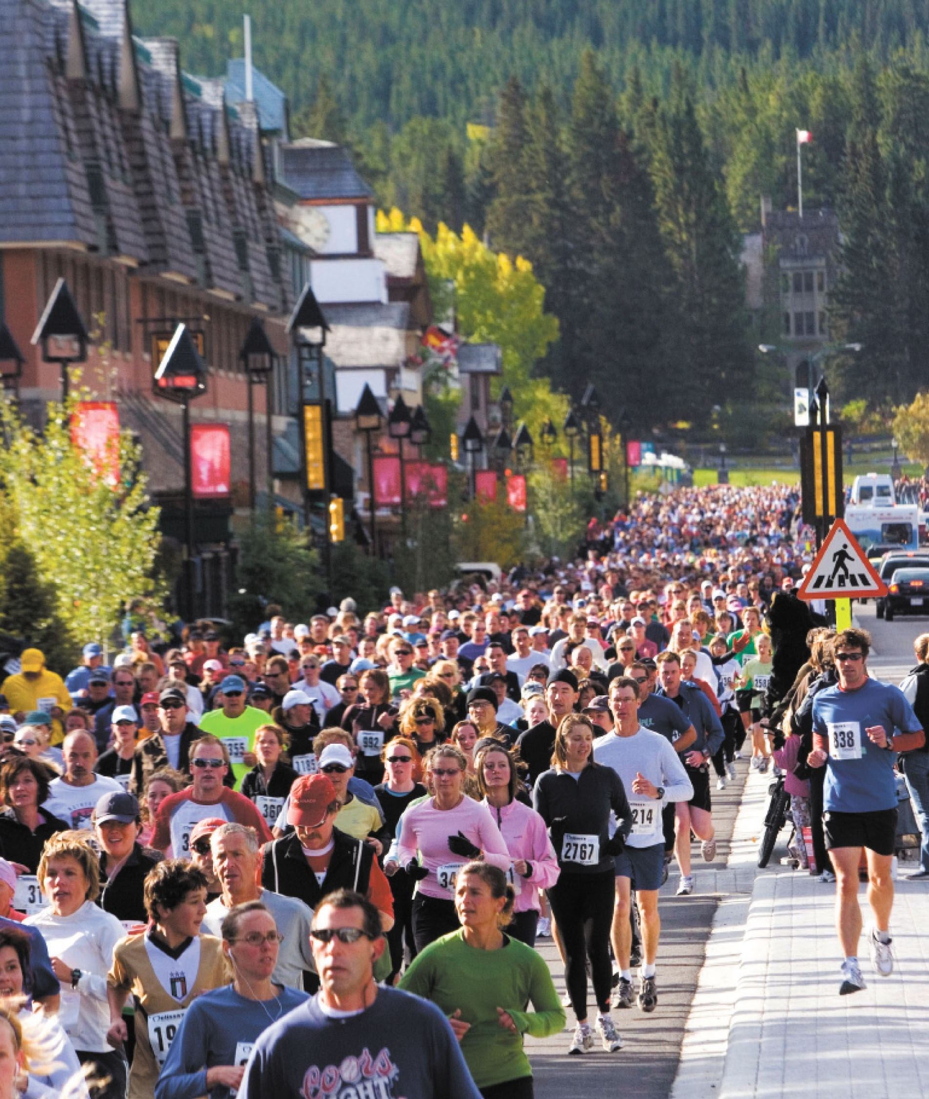 Large crowd of runners moving through a busy downtown street.