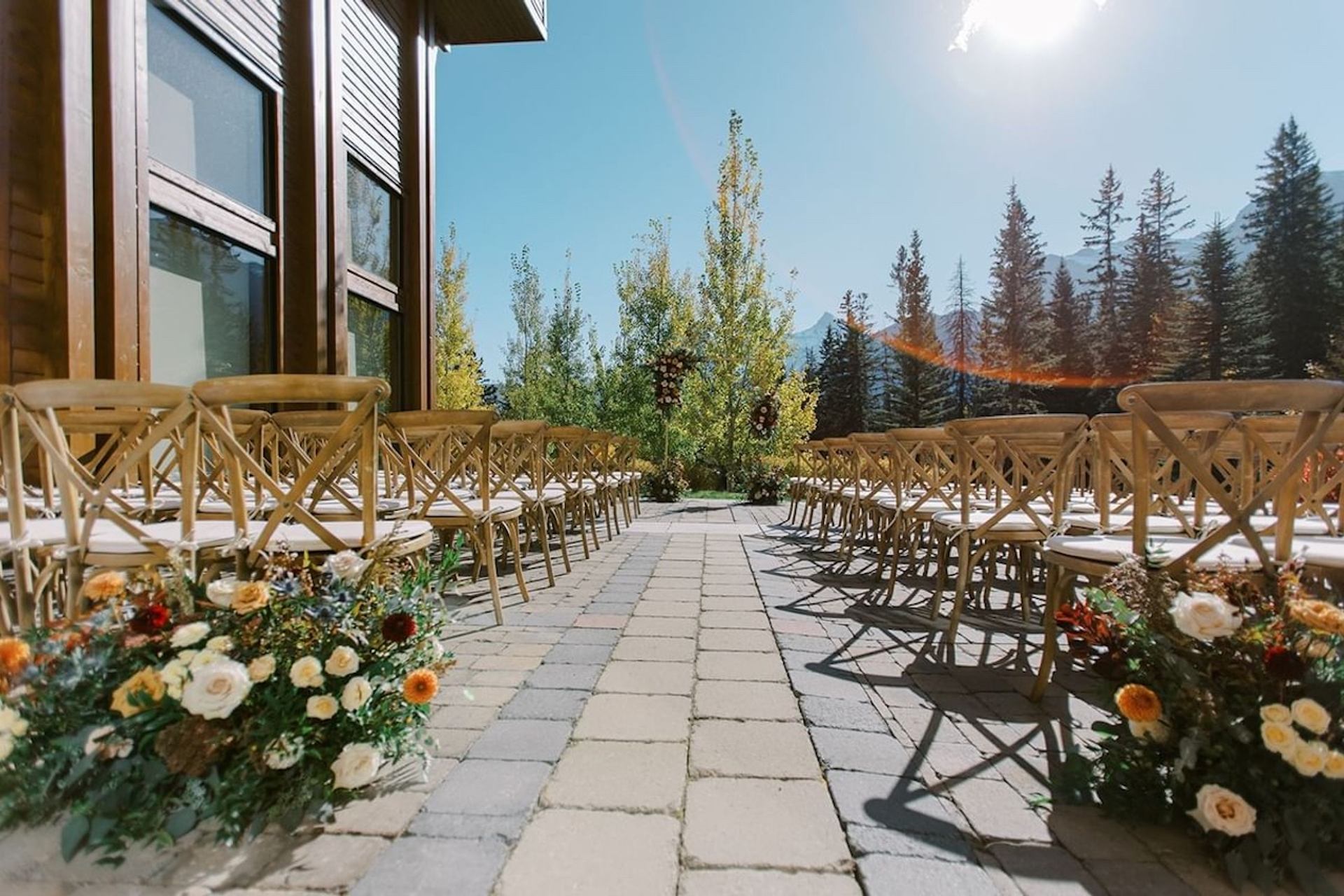 Outdoor wedding aisle lined with wooden chairs and floral arrangements