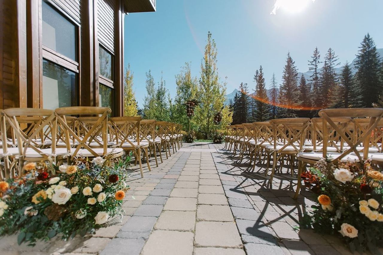 Outdoor wedding aisle lined with wooden chairs and floral arrangements