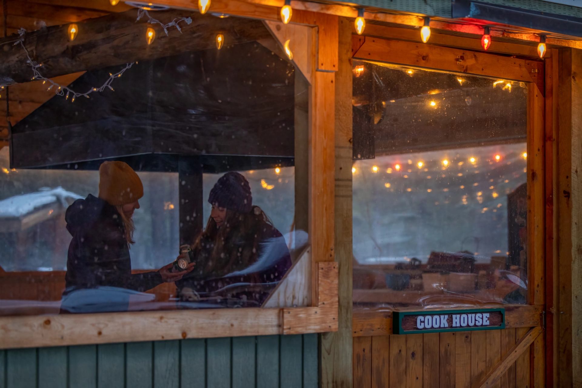 Guests relaxing inside the Cookhouse beneath warm string lights on a cozy evening.