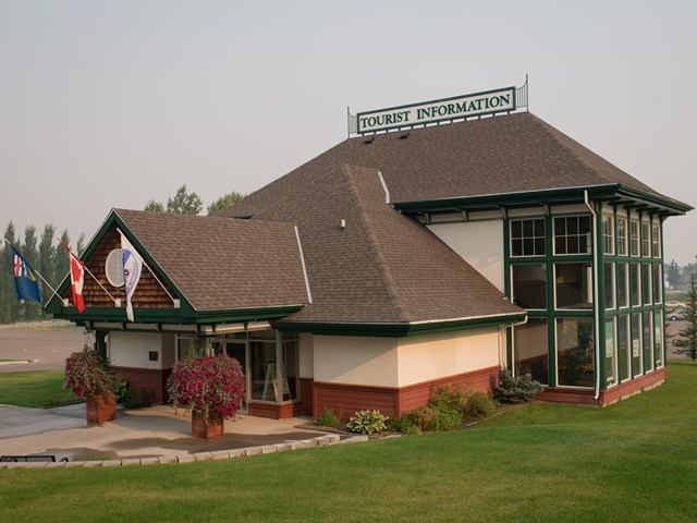 Cardston VIC building with flags, angled roof, and 'TOURIST INFORMATION' sign.