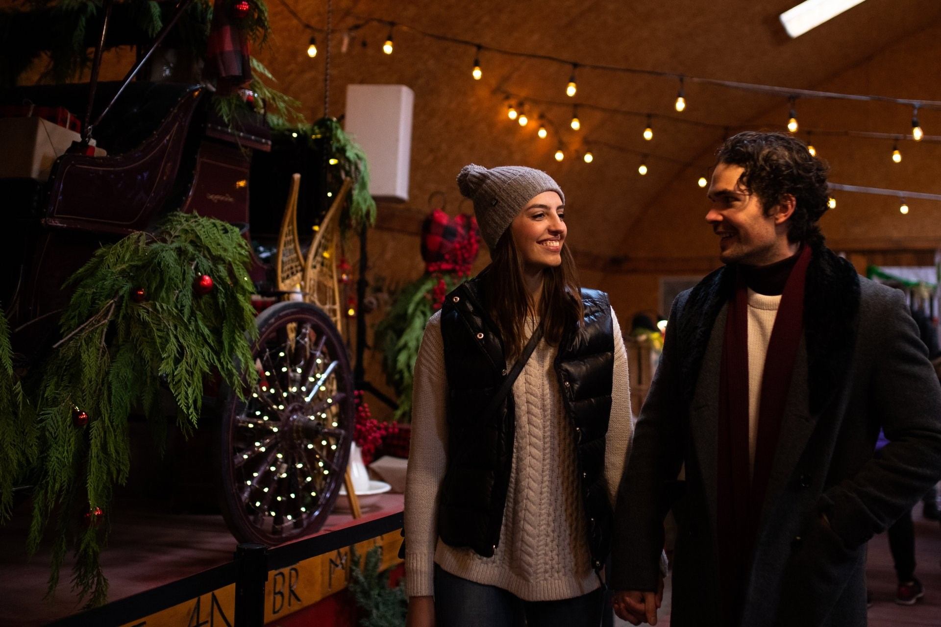 A couple walks hand in hand next to a Christmas display.