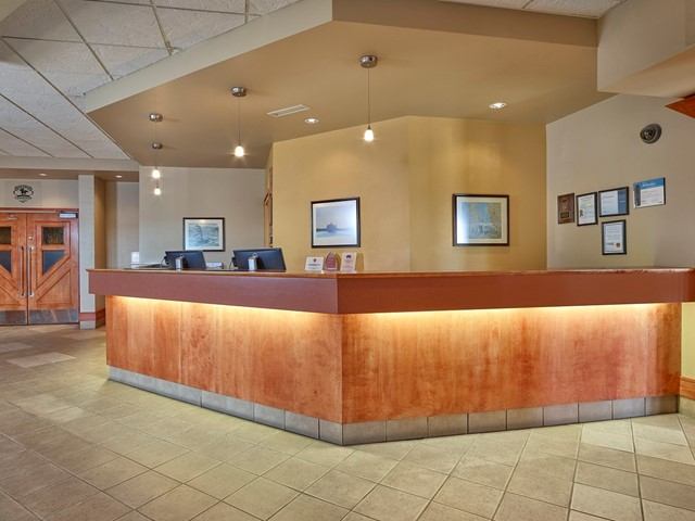 Hotel reception desk with pendant lights, framed pictures, and bulletin boards in lobby.