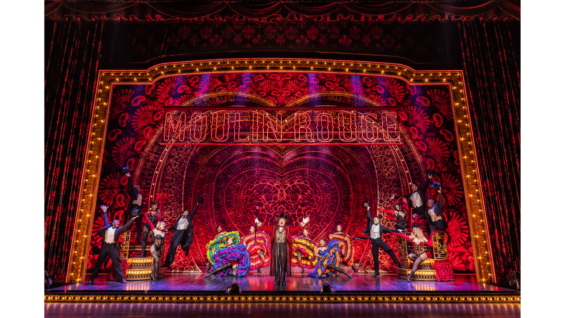 Theatrical stage with performers, ornate backdrop, and “MOULIN ROUGE!” marquee lights.
