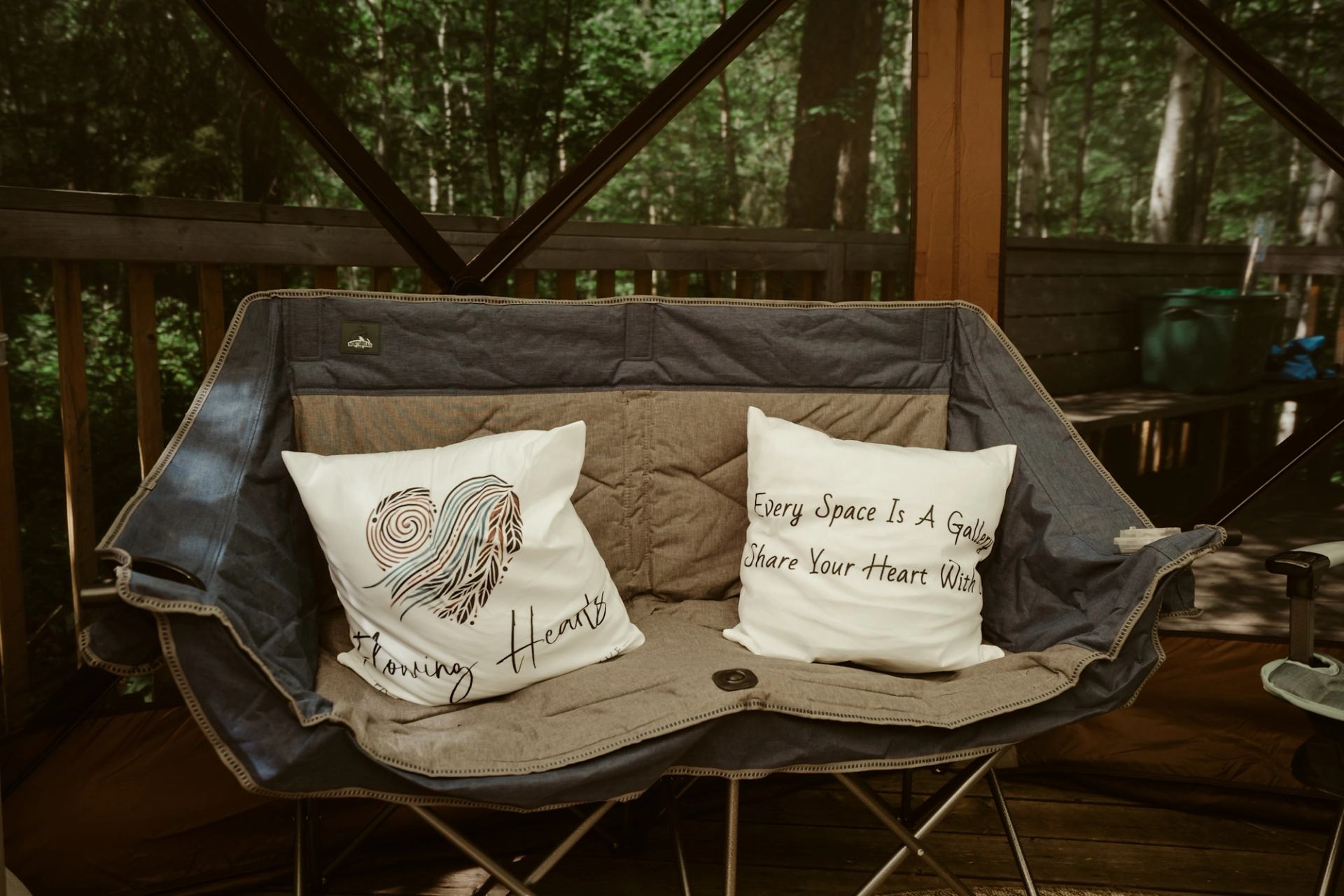 Bench with two printed cushions inside a wooden structure surrounded by trees.