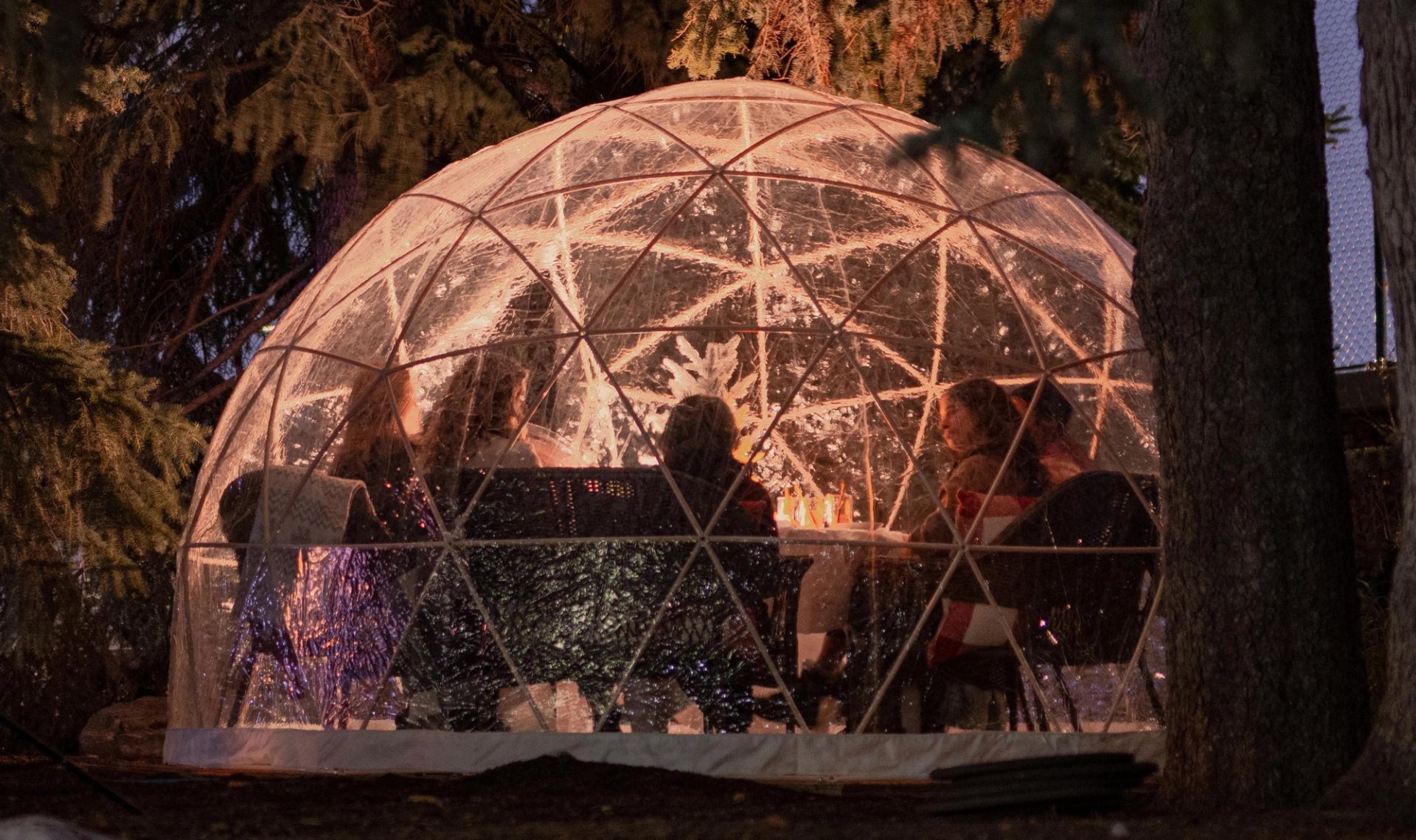 Glowing transparent dome surrounded by colorful lights in a snowy outdoor setting.