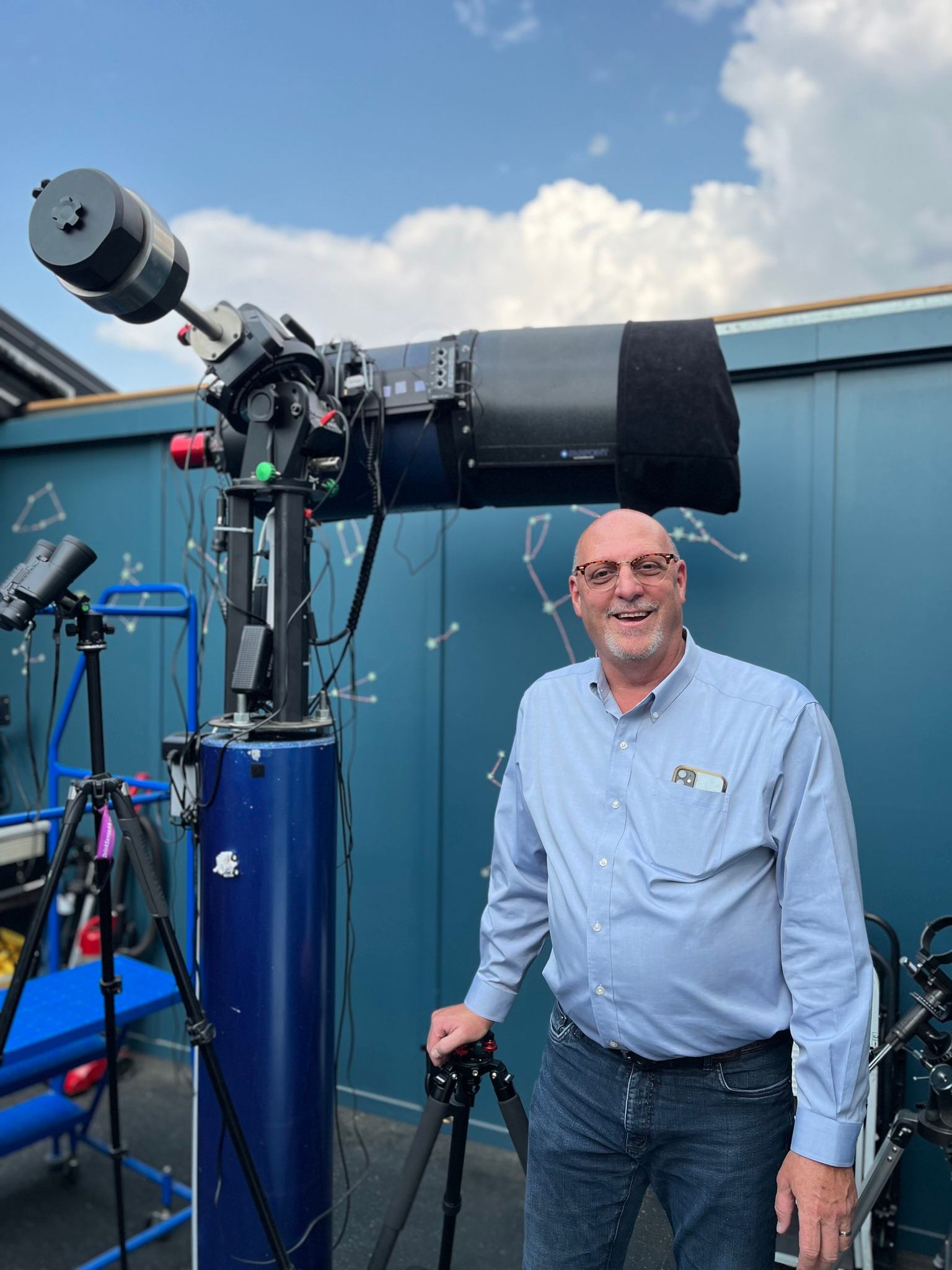 Man beside telescope on rooftop observatory.