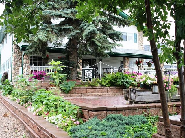Charming stone house with rustic decor, vibrant flowers, lush greenery, and an inviting entrance.