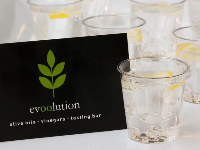 evolution olive oils and vinegar tasting bar sign with clear sample cups on table.