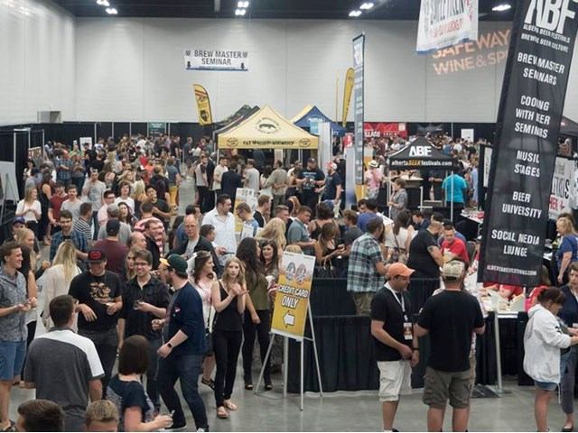 Busy indoor beer festival with booths, banners, and mingling attendees.