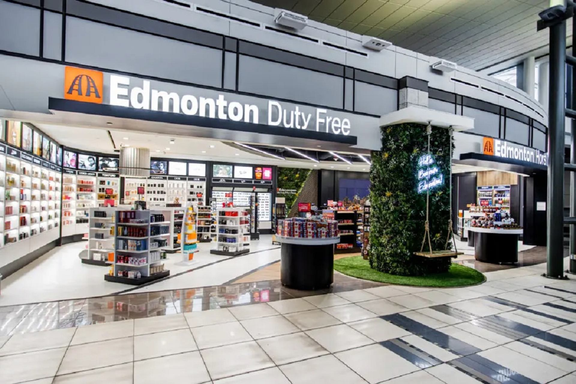 Edmonton Duty Free shop interior with shelves of products and a plant-covered pillar featuring a wooden swing.