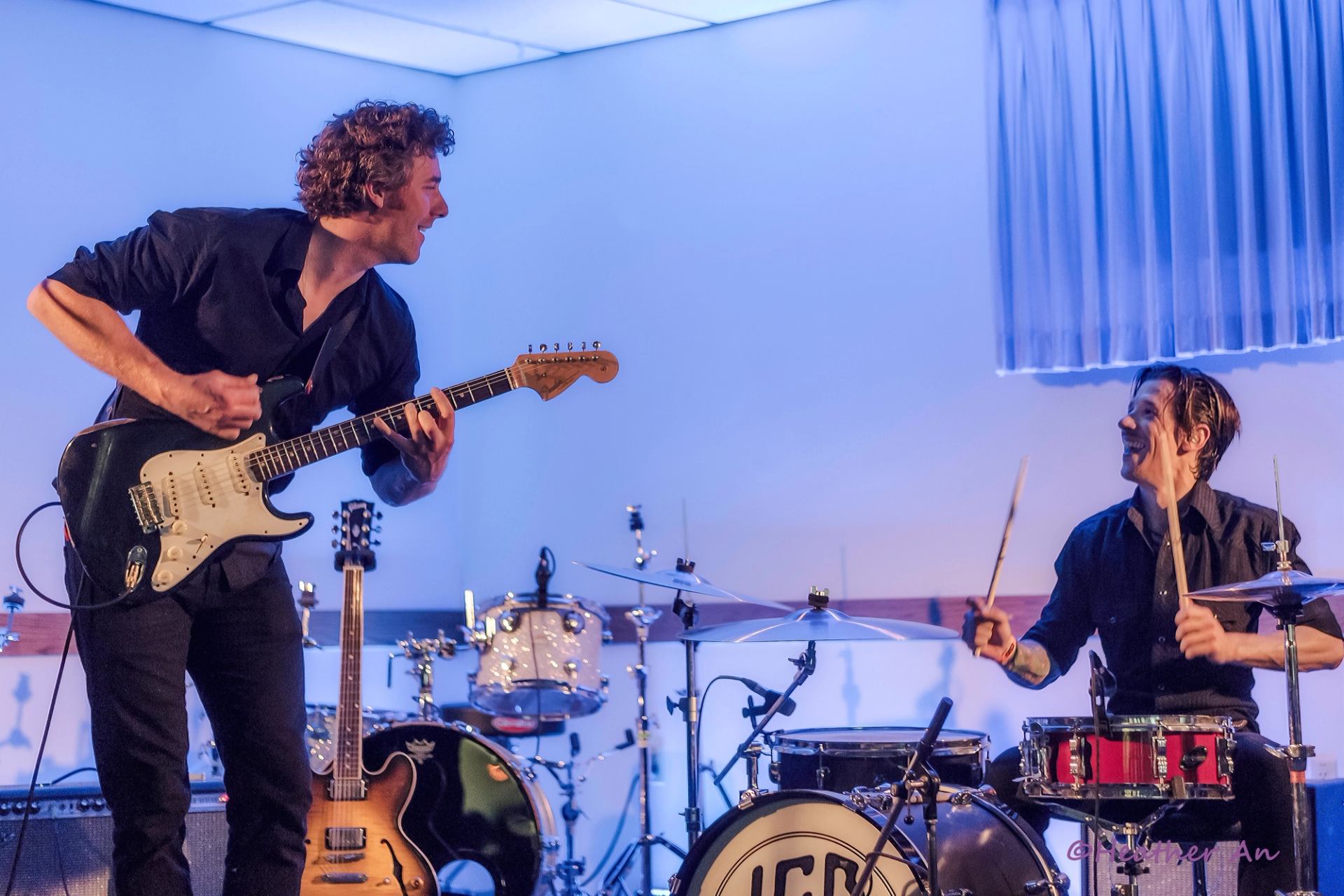 Guitarist and drummer performing on stage with instruments and drum kit at East Coulee SpringFest.