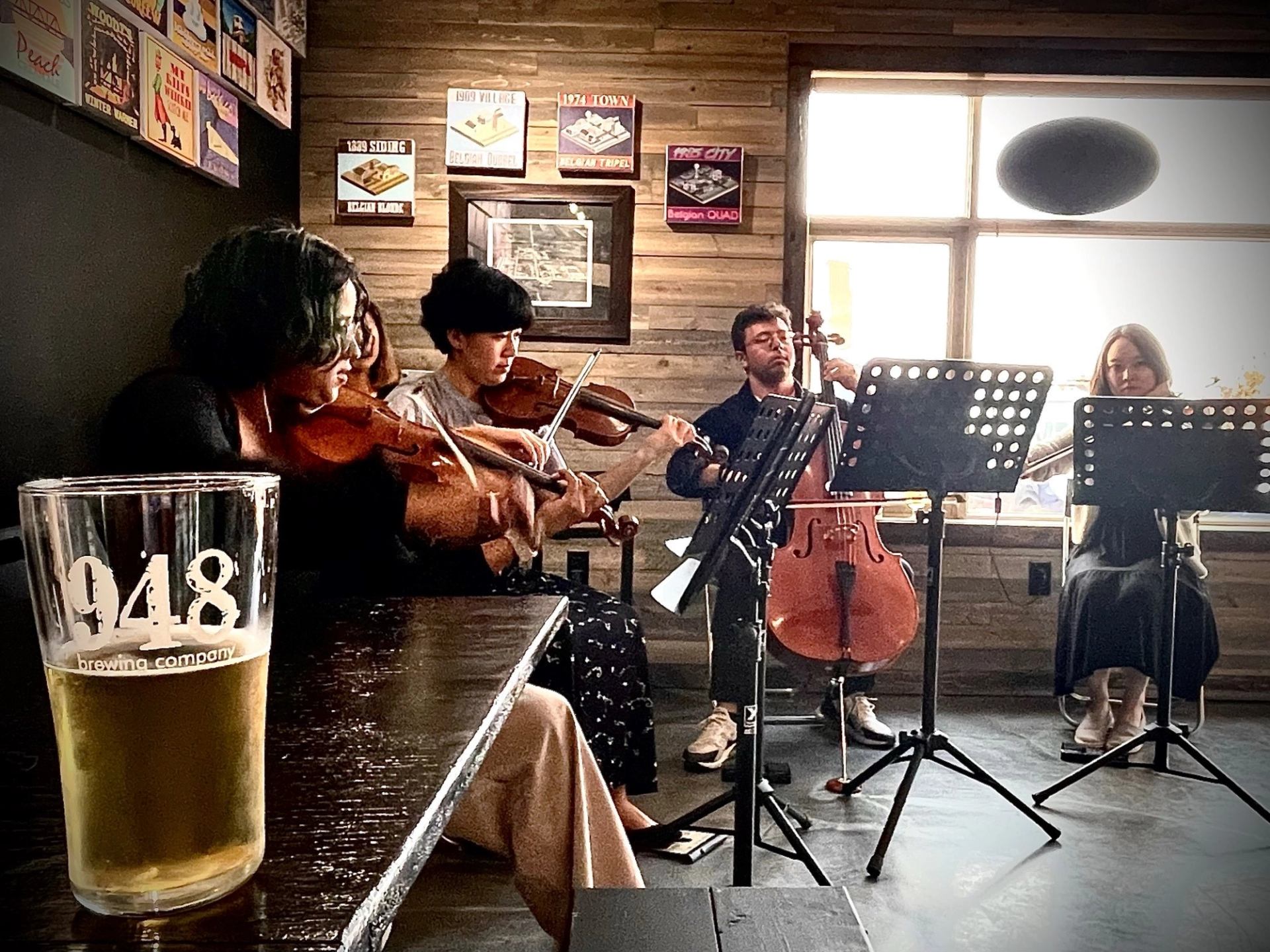 String quartet performs in a bar beside a beer glass labelled 948 Brewing Company.