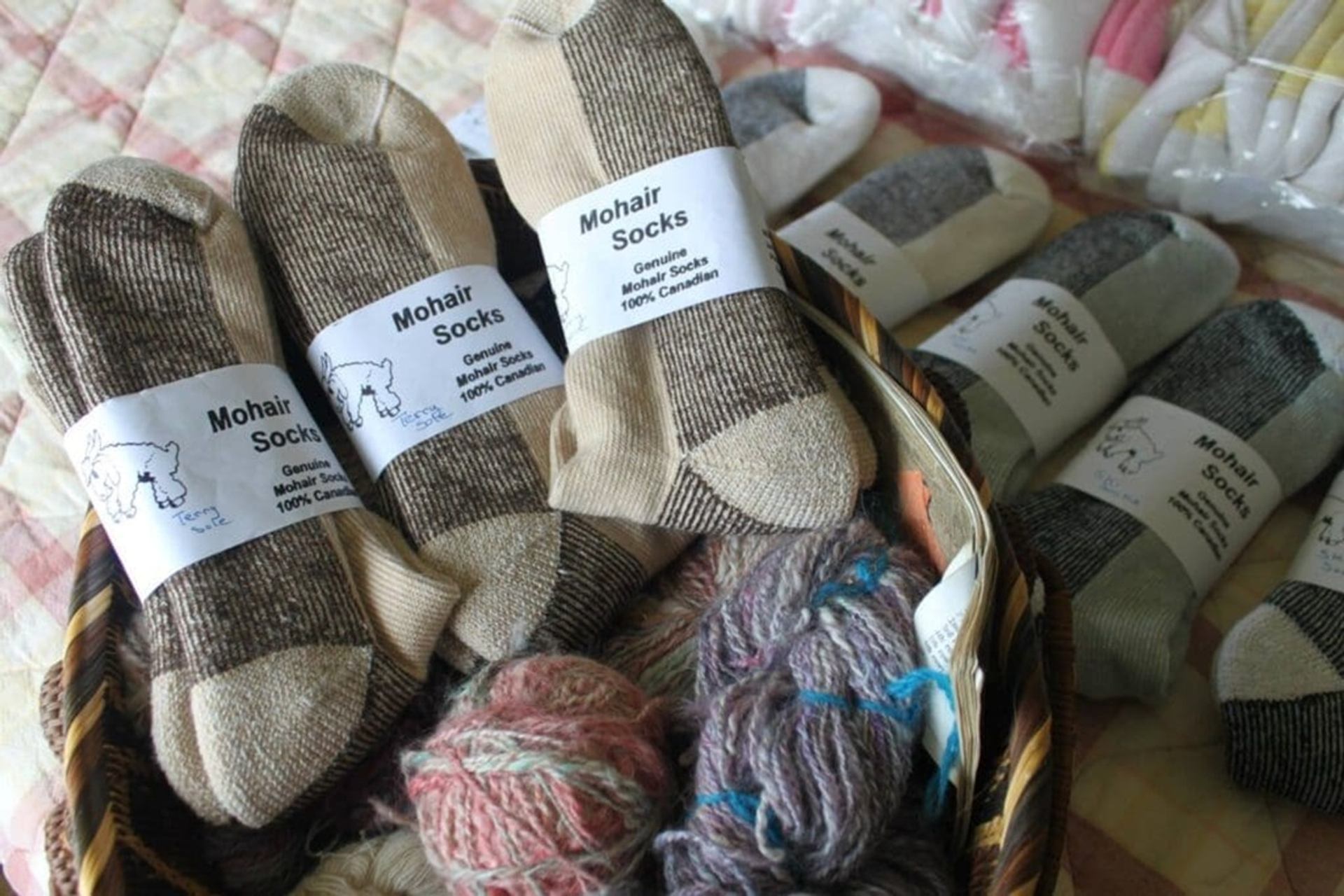 A basket filled with mohair socks and balls of yarn is arranged on a soft surface, with product labe