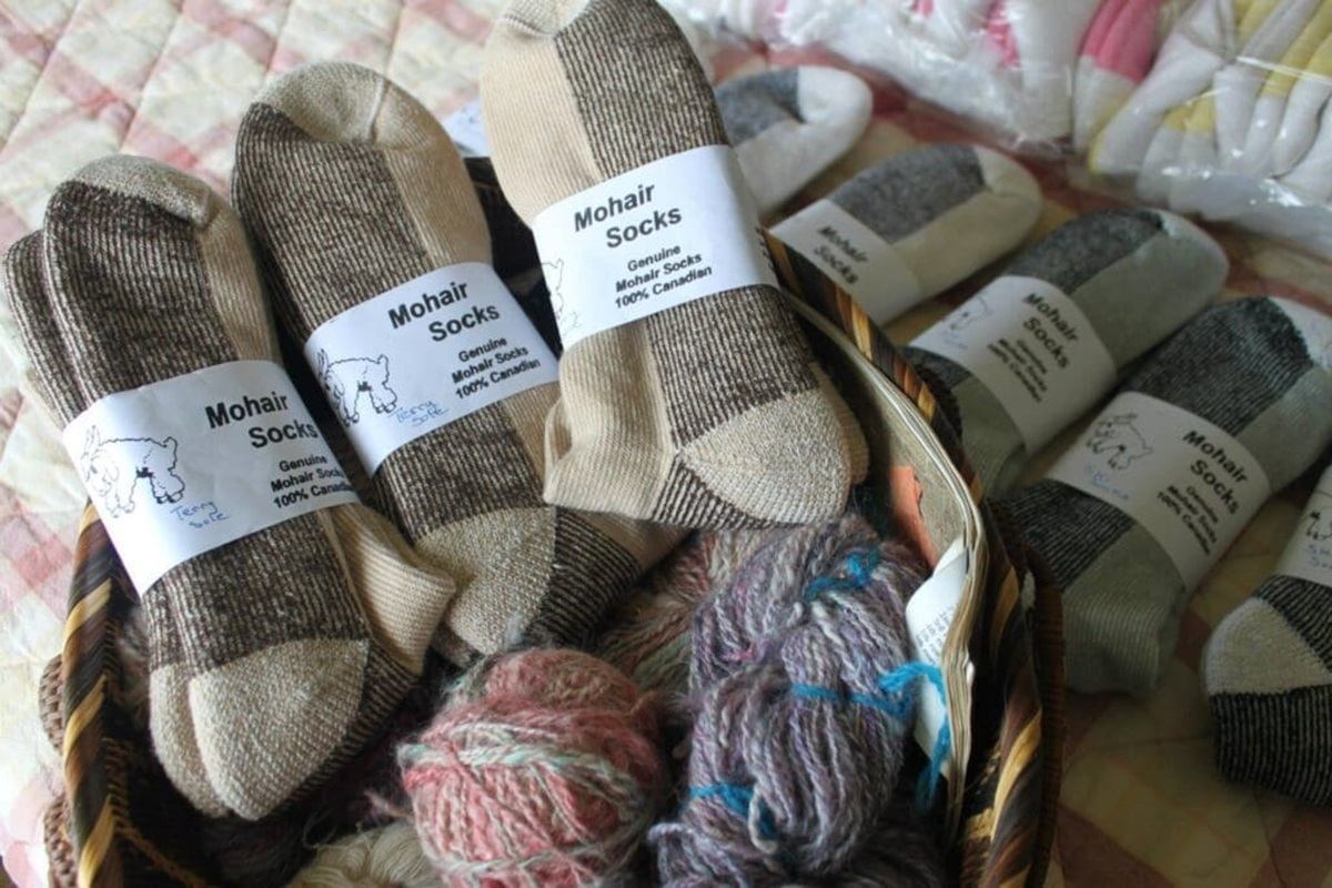 A basket filled with mohair socks and balls of yarn is arranged on a soft surface, with product labe