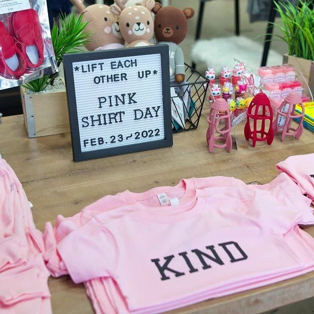 Kid’s clothing display with pink T-shirts, stools, and a sign reading “Pink Shirt Day.”