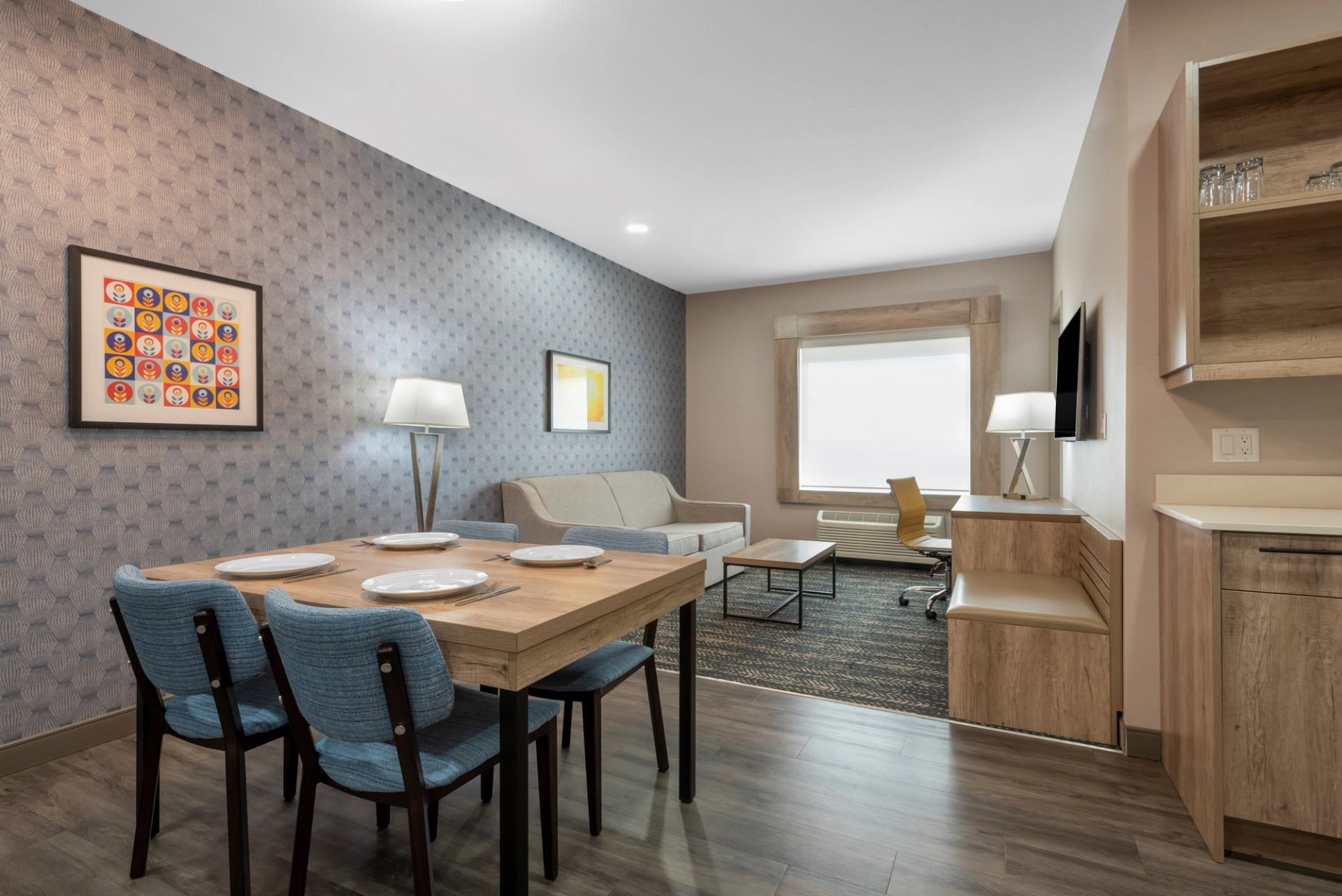 Modern hotel suite with dining, living area, and kitchenette.