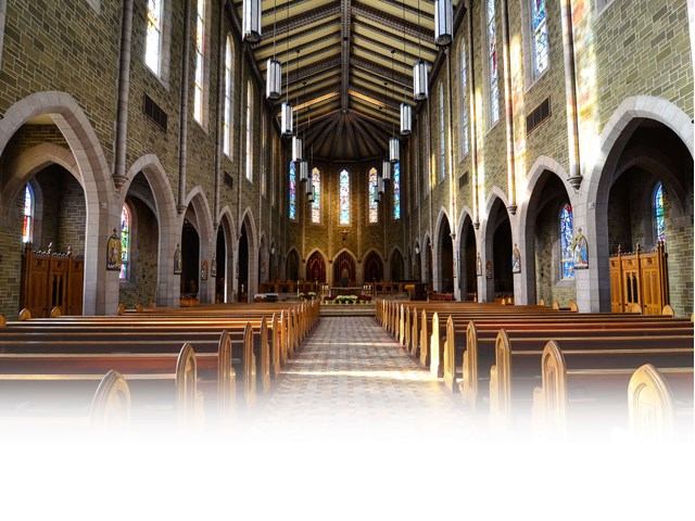 Interior of St. Joseph’s Basilica with stone arches, wooden pews, and stained glass windows.