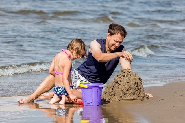 Father and daughter building a sand castle on the beach.