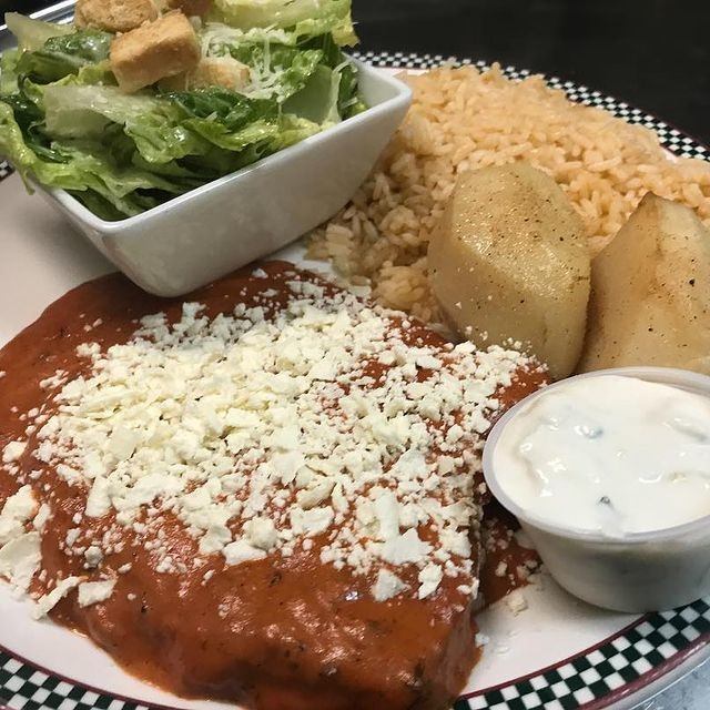 Greek dish with tomato sauce, feta, rice, potatoes, salad, and tzatziki.