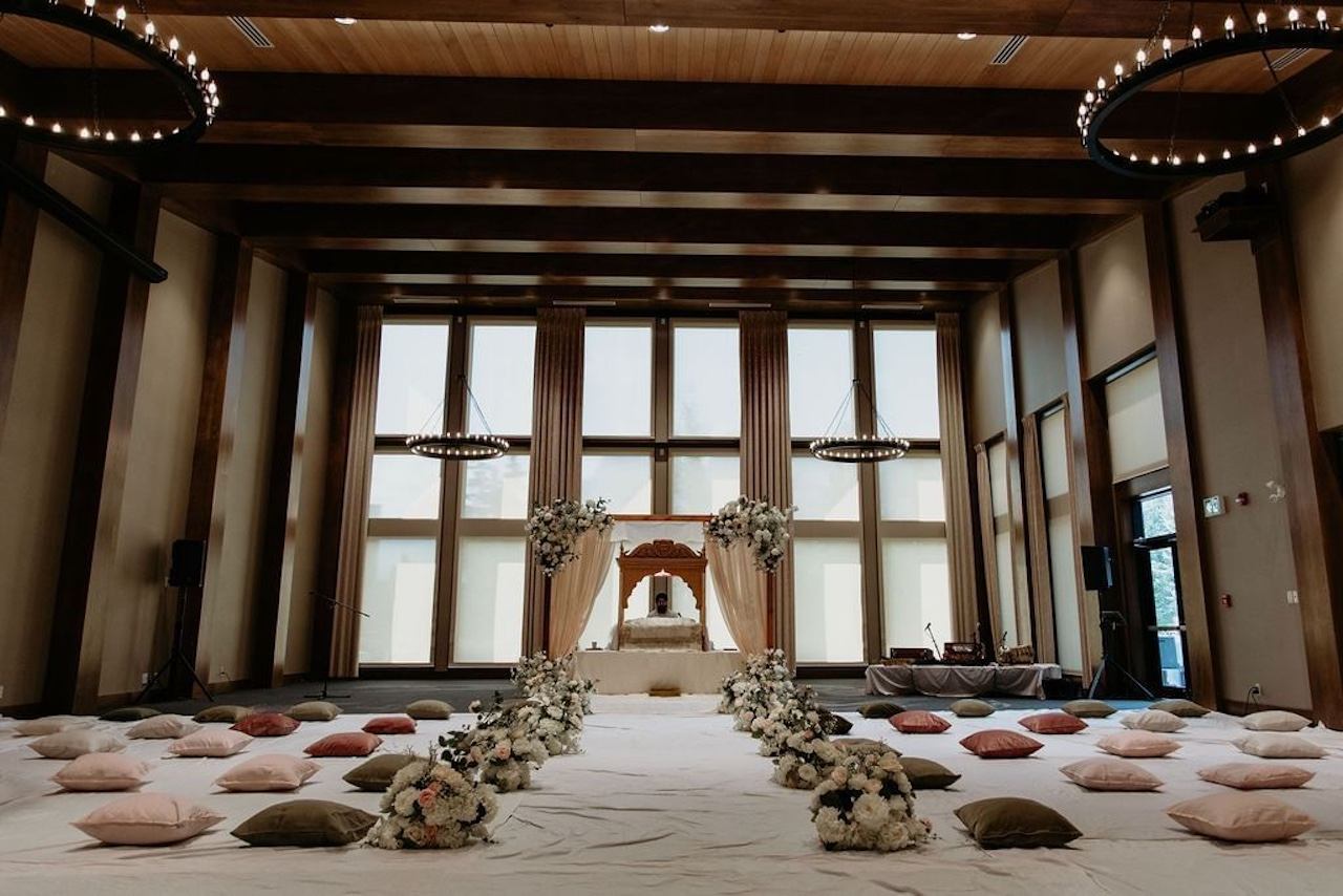 Indoor ceremony room with floral aisle, soft pillows, and draped altar