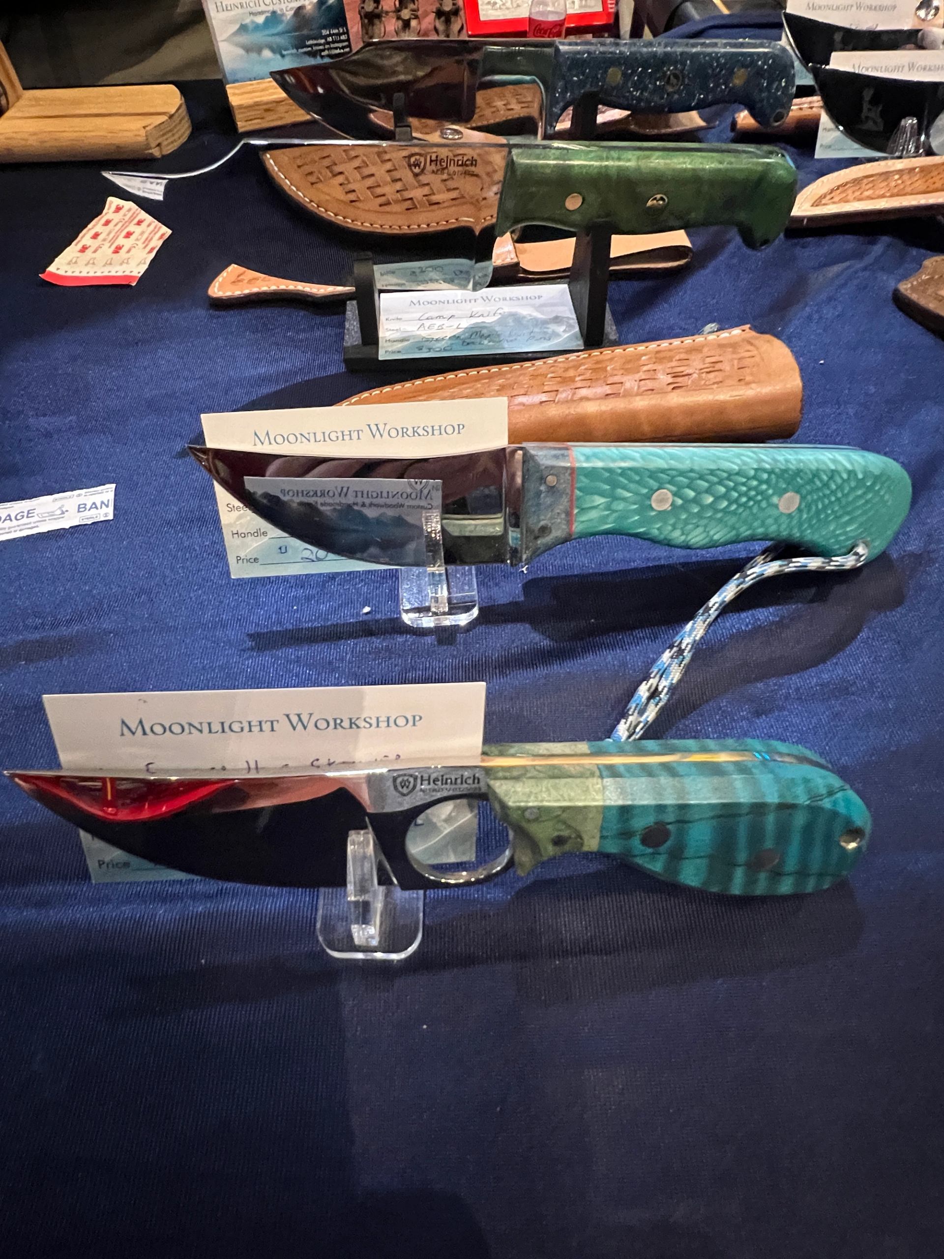 Display of handmade knives with decorative handles on a table.