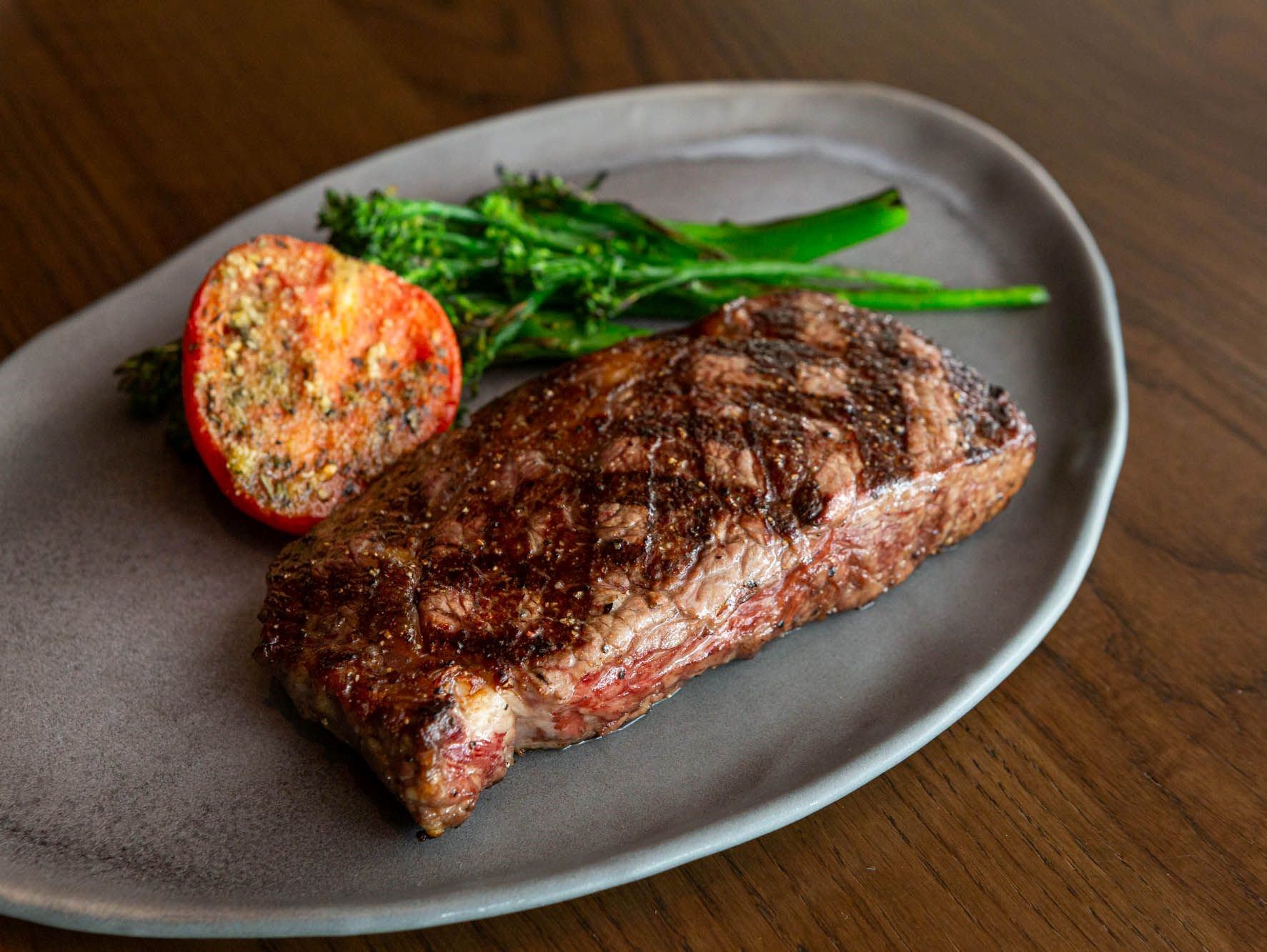 Juicy grilled steak served with broccolini and roasted tomato on a plate