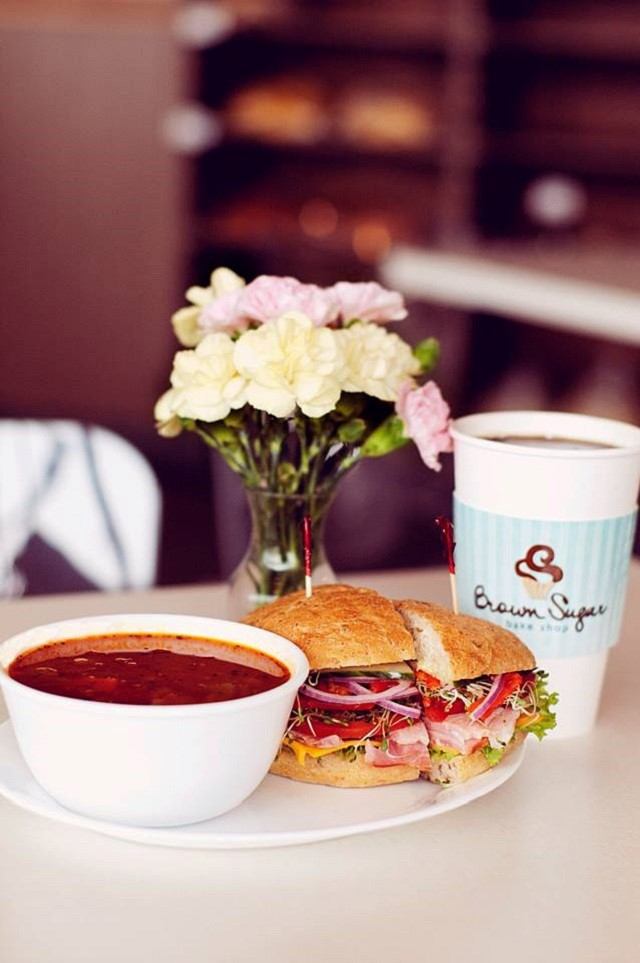 A hearty sandwich with soup and a Brown Sugar Bake Shop coffee cup on a table
