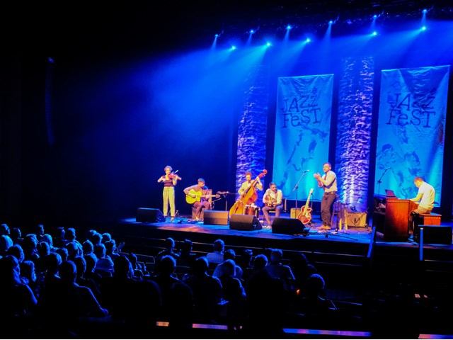 Jazz ensemble performs under blue stage lights at Medicine Hat JazzFest.