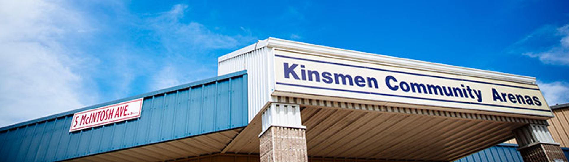Exterior view of Kinsmen Community Arenas building with signage and covered entrance.