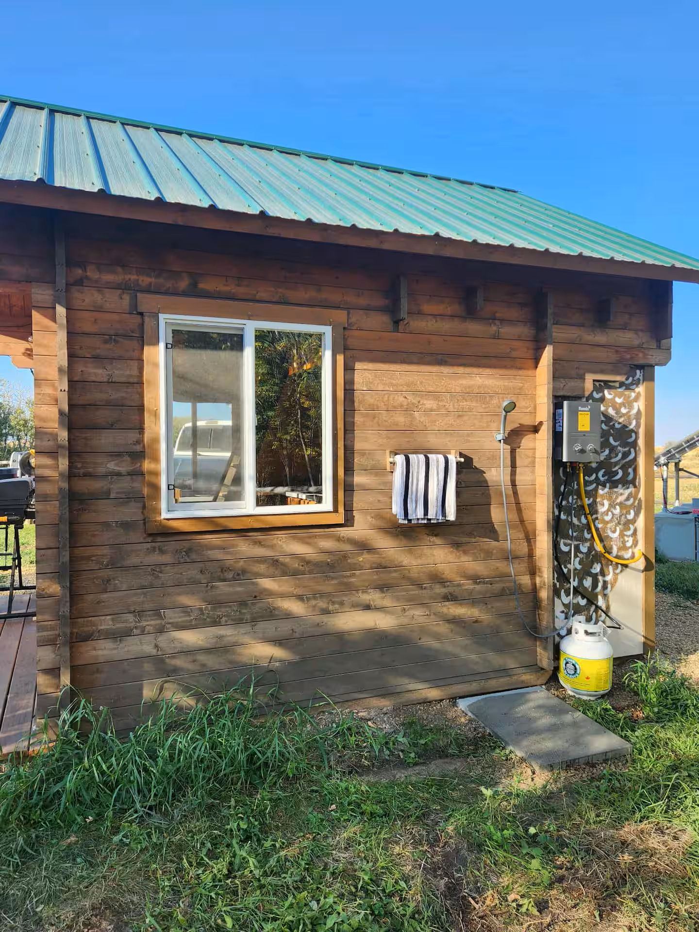 Cabin exterior with a mounted outdoor shower and propane water heater.